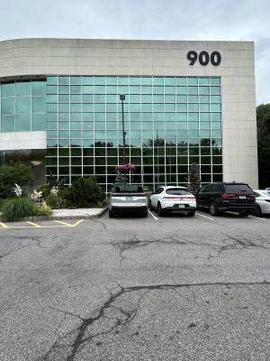 picture of the outside of 900 South Ave. The entrance is to the left and the sidewalks are surrounded by blooming landscaping.